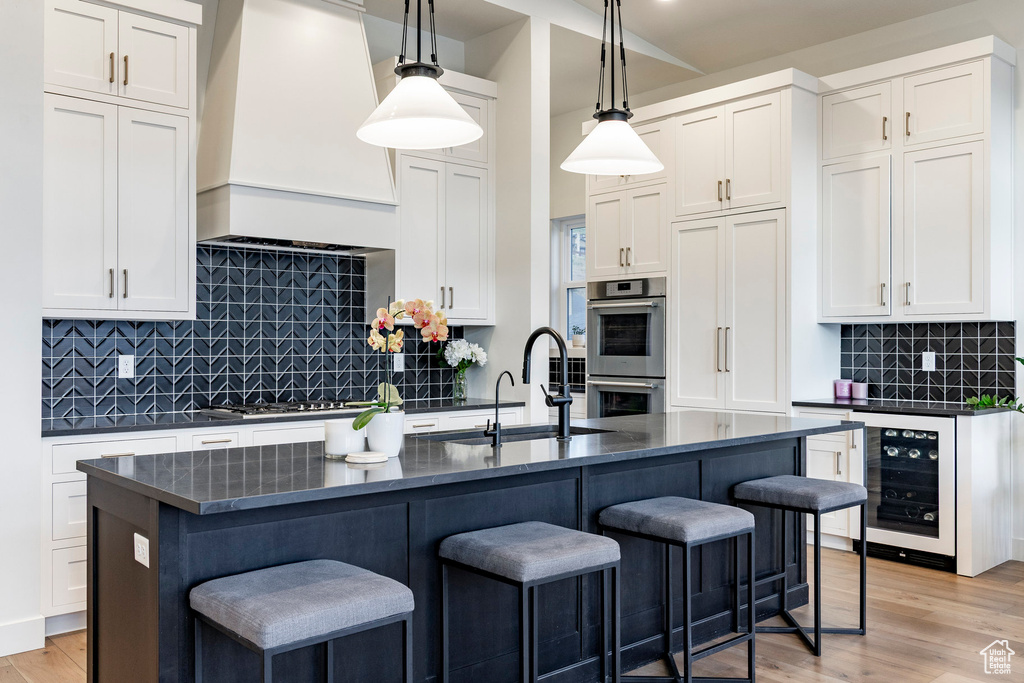 Kitchen with wine cooler, stainless steel double oven, a breakfast bar, and white cabinets