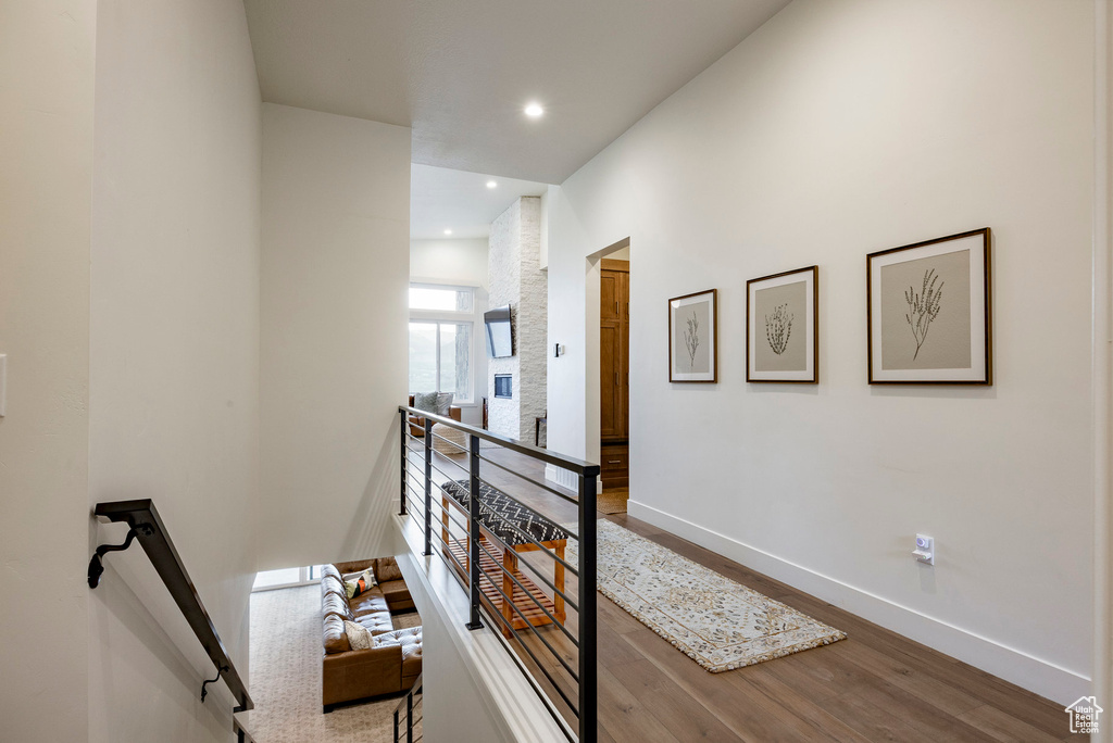 Hallway featuring an upstairs landing, wood finished floors, and recessed lighting