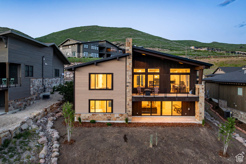 Rear view of property with stone siding, a mountain view, a balcony, and a chimney