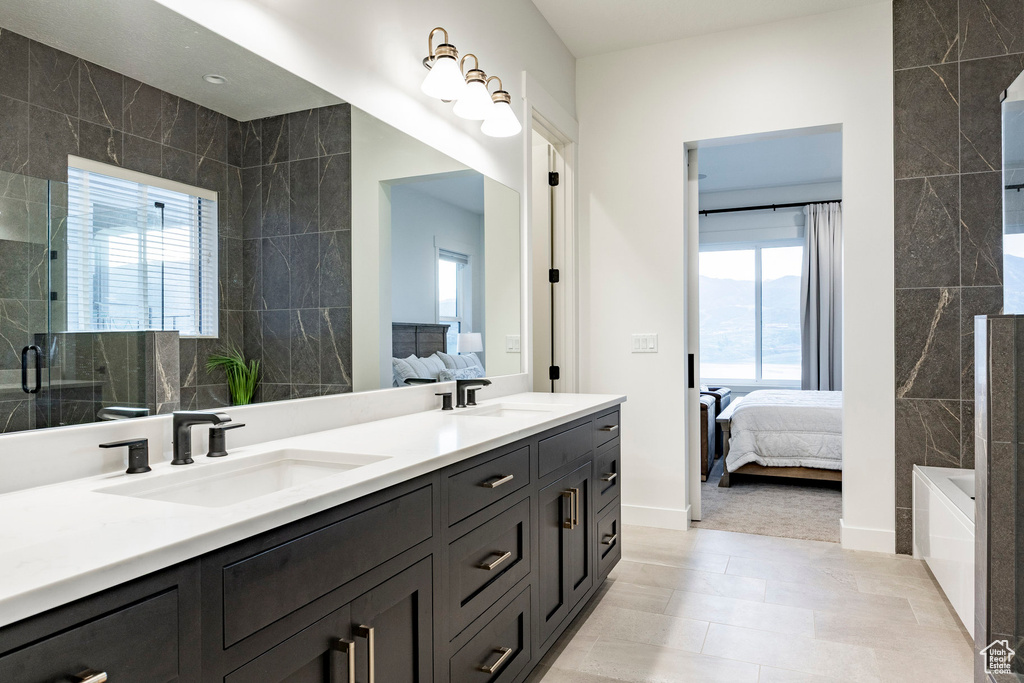 Bathroom with ensuite bath, tile walls, double vanity, an enclosed shower, and a tub to relax in