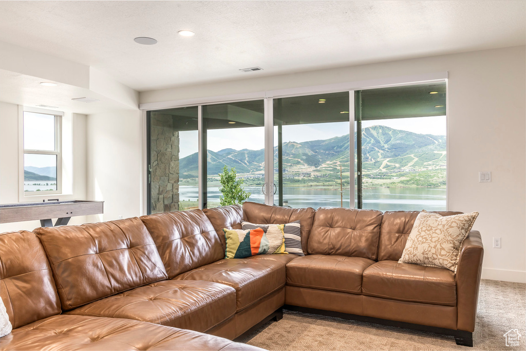 Living area with light colored carpet, recessed lighting, and a water and mountain view