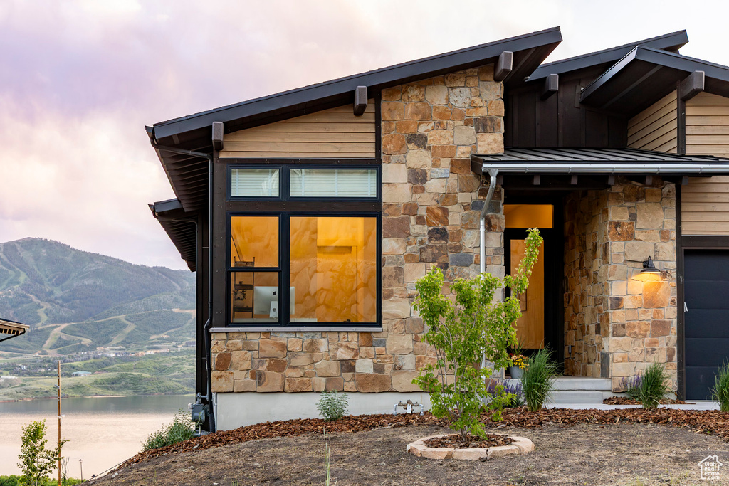 View of front of house featuring stone siding, board and batten siding, and a water and mountain view