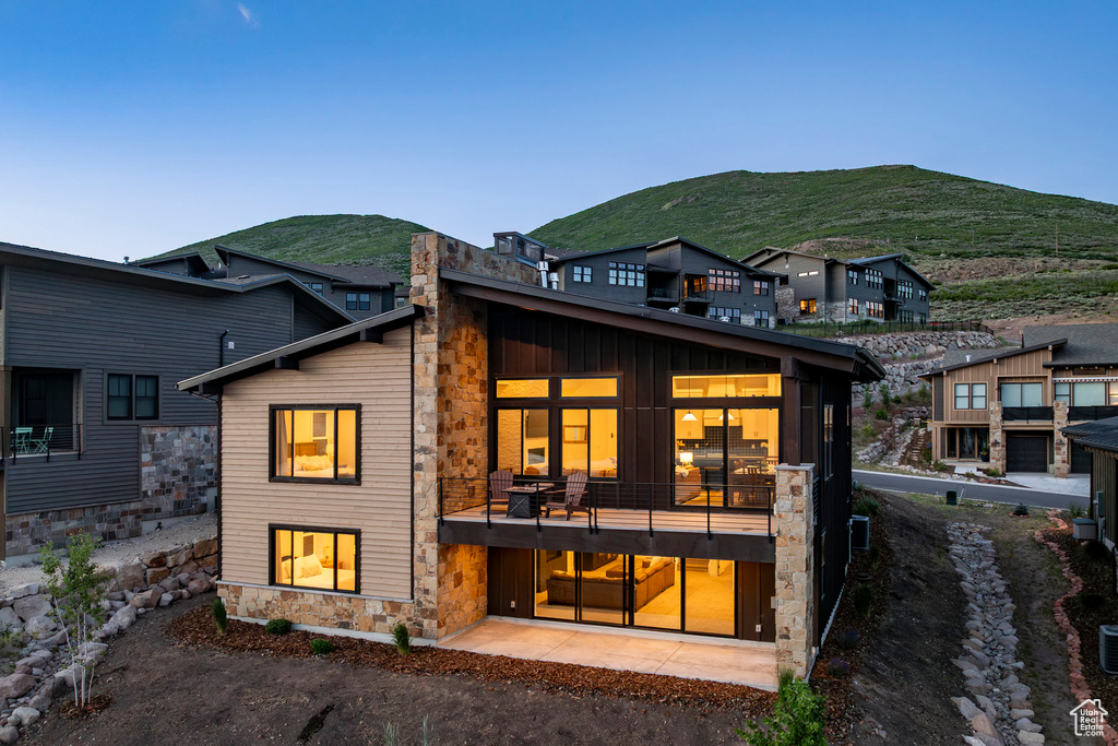 Back of house with stone siding, a mountain view, and a balcony