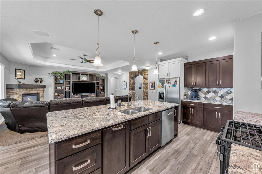 Kitchen featuring stainless steel appliances, a raised ceiling, open floor plan, and recessed lighting