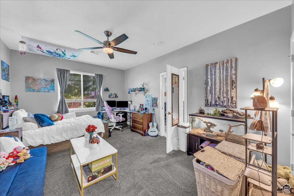 Carpeted living area featuring ceiling fan and a desk