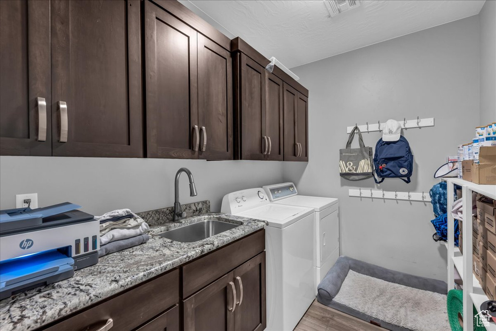 Washroom with cabinet space, independent washer and dryer, and light wood-type flooring