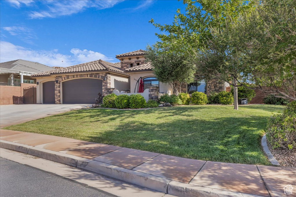 Mediterranean / spanish house featuring stucco siding, a tile roof, a garage, concrete driveway, and stone siding