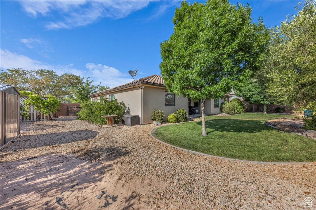 Rear view of house featuring a fenced backyard, stucco siding, and a tiled roof