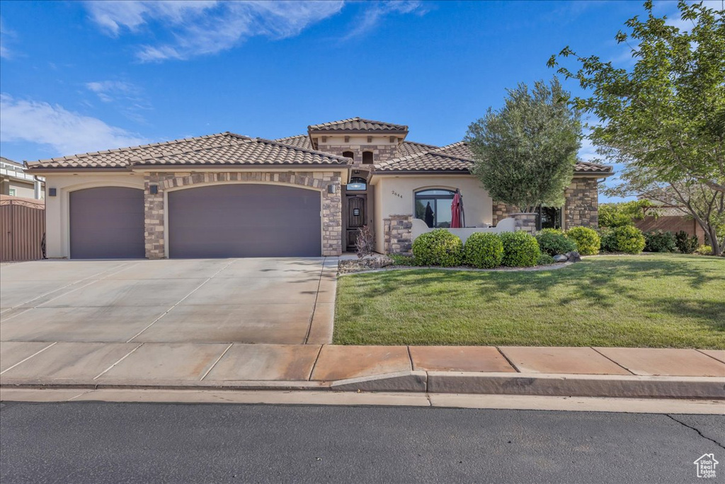 Mediterranean / spanish-style house featuring stucco siding, a garage, a tile roof, and concrete driveway