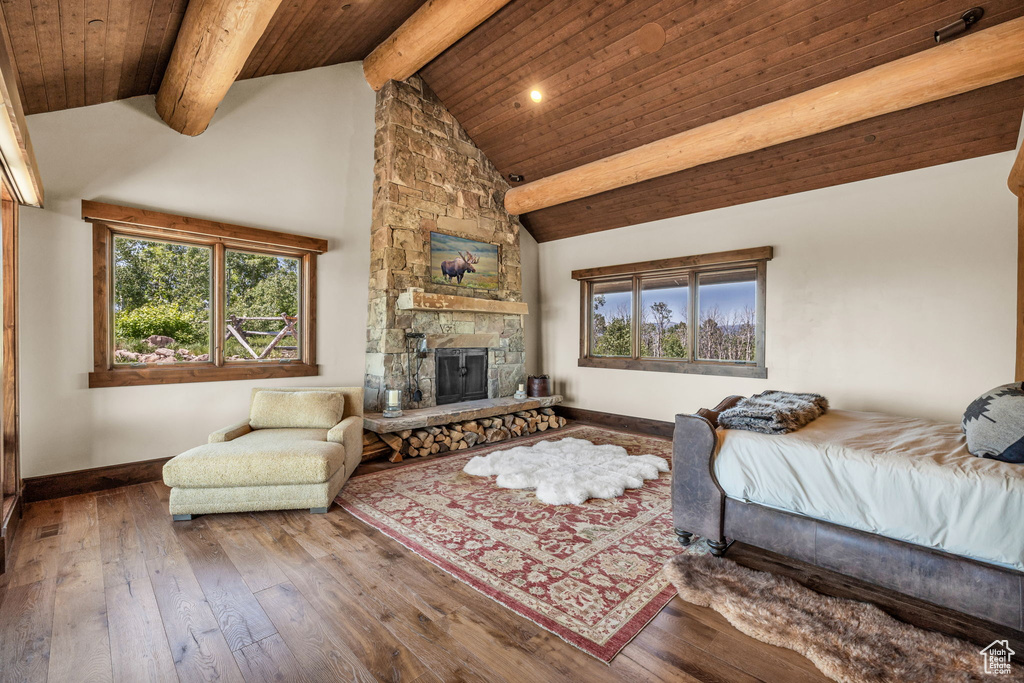 Bedroom featuring multiple windows, a wooden ceiling with exposed beams, hardwood / wood-style flooring, a fireplace, and high vaulted ceiling