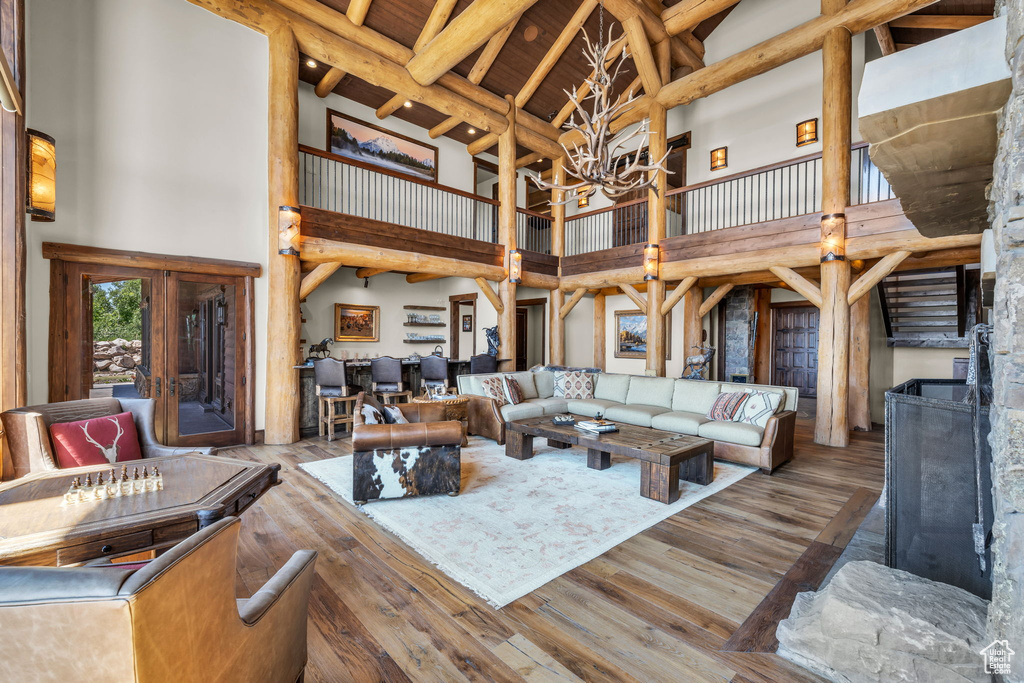 Living room featuring high vaulted ceiling, a chandelier, wood finished floors, and beam ceiling
