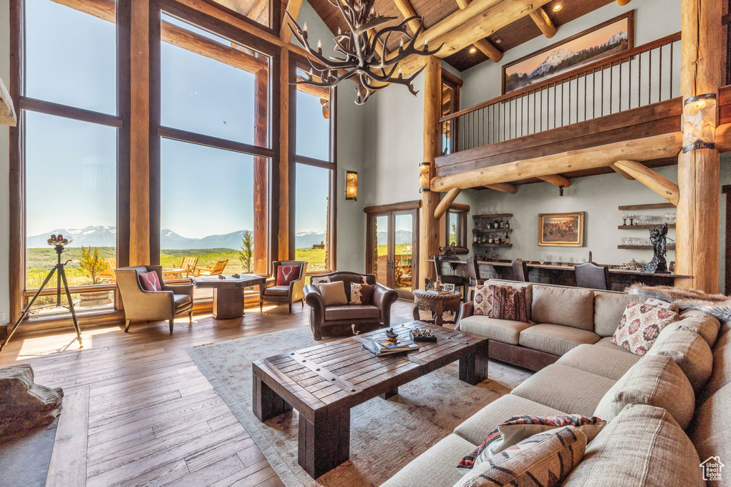 Living area featuring a high ceiling, a chandelier, hardwood / wood-style floors, a mountain view, and a wood ceiling with exposed beams