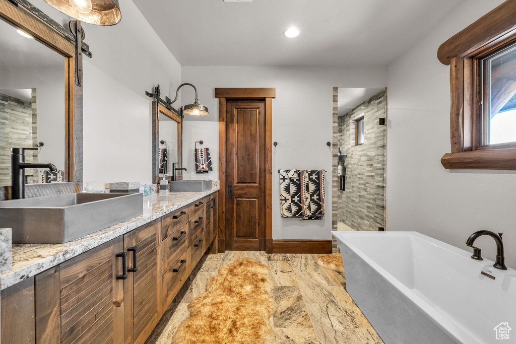 Full bath featuring a freestanding tub, double vanity, a shower, and recessed lighting