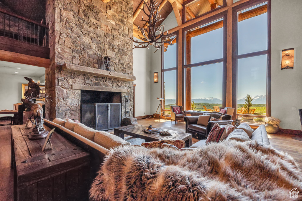 Living room featuring high vaulted ceiling, wood finished floors, a chandelier, and a fireplace