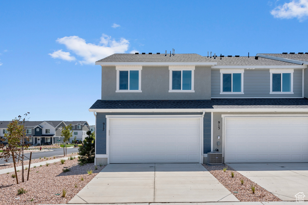 View of front of home with concrete driveway, a garage, a residential view, and a shingled roof