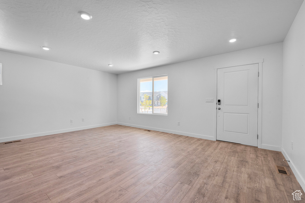 Spare room with light wood finished floors, recessed lighting, and a textured ceiling