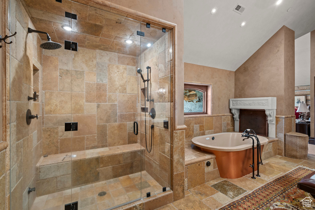 Bathroom with a soaking tub, a stall shower, stone tile floors, vaulted ceiling, and recessed lighting