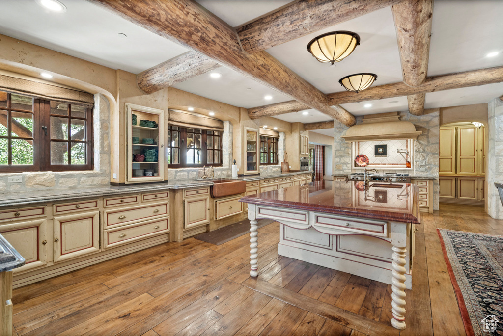 Kitchen featuring cream cabinets, decorative backsplash, light wood-style floors, beamed ceiling, and coffered ceiling