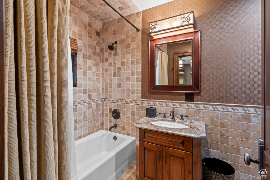 Full bathroom with tile walls, shower / tub combo with curtain, vanity, and tile patterned floors