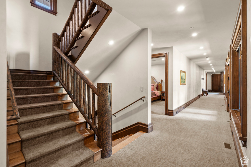 Stairs with carpet floors and recessed lighting