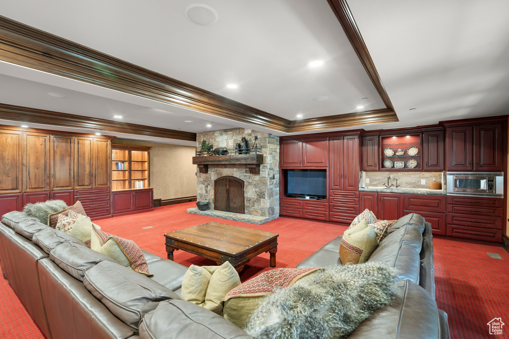 Living area with crown molding, a fireplace, a baseboard radiator, a tray ceiling, and dark colored carpet