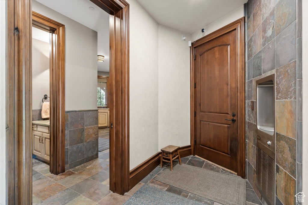 Foyer featuring stone tile floors and tile walls