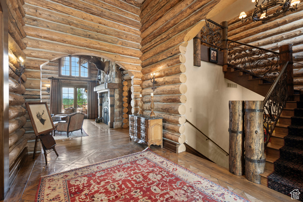 Entryway with arched walkways, log walls, wood-type flooring, and a towering ceiling
