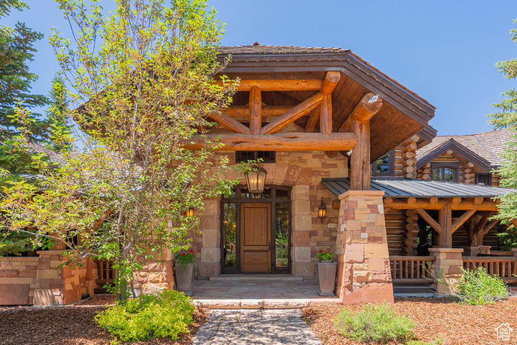 Property entrance featuring log exterior, covered porch, and stone siding