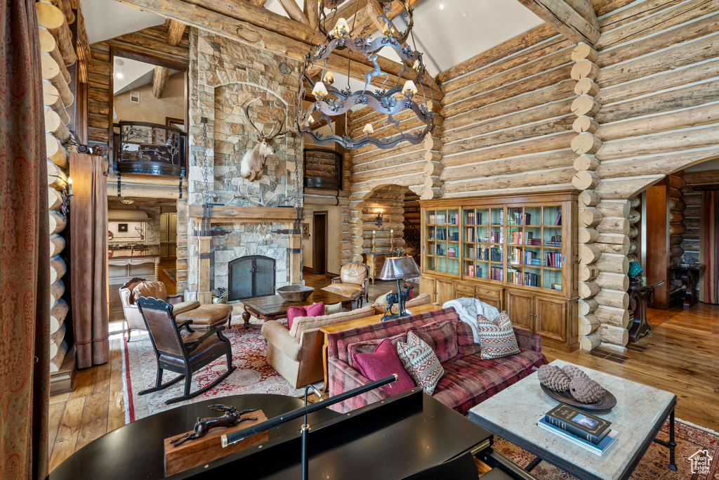 Living area featuring high vaulted ceiling, arched walkways, beamed ceiling, log walls, and hardwood / wood-style floors