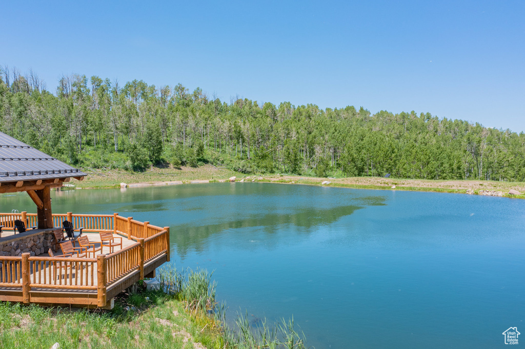 Dock featuring a view of trees, a gazebo, and a deck with water view