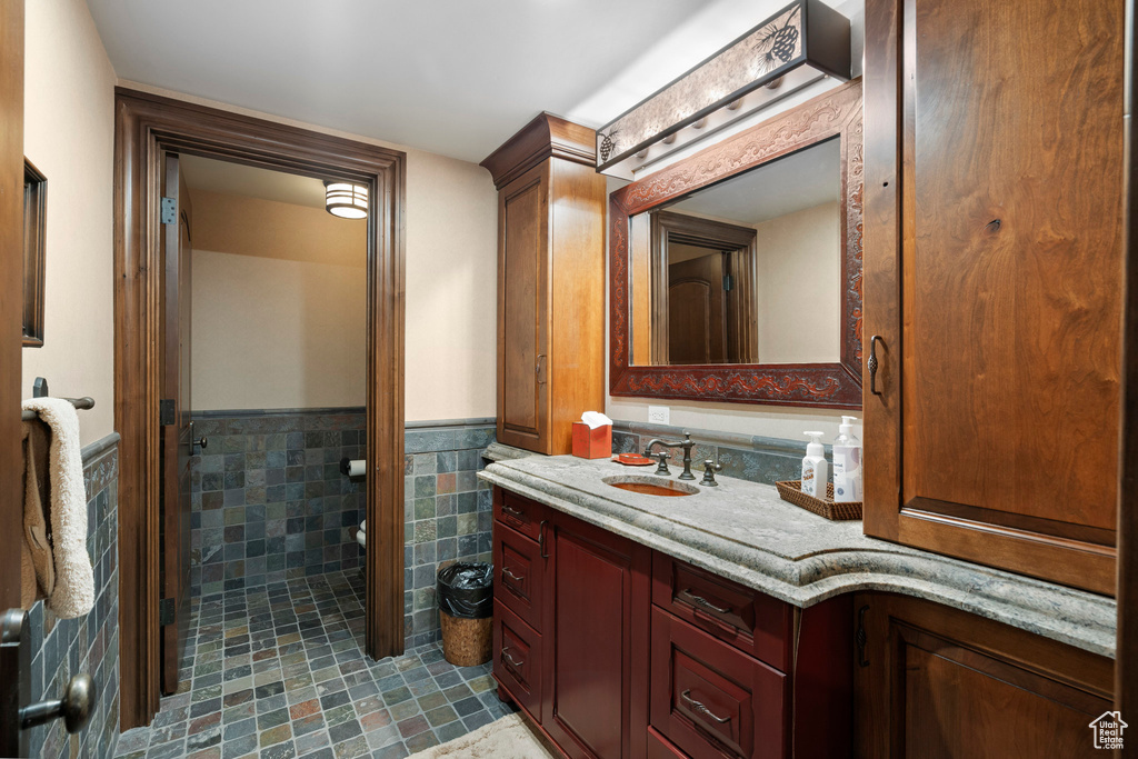 Bathroom featuring vanity, wainscoting, tile patterned flooring, and tile walls