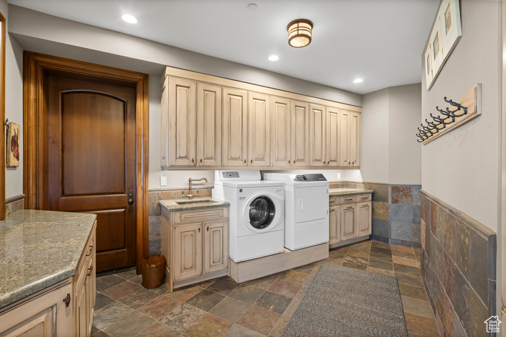 Laundry area with stone tile flooring, cabinet space, washing machine and clothes dryer, recessed lighting, and a wainscoted wall