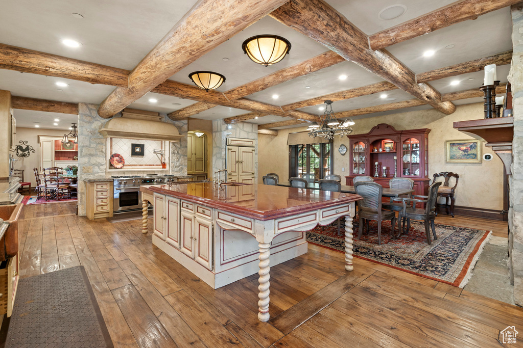 Kitchen with backsplash, wood-type flooring, stainless steel range, beamed ceiling, and coffered ceiling