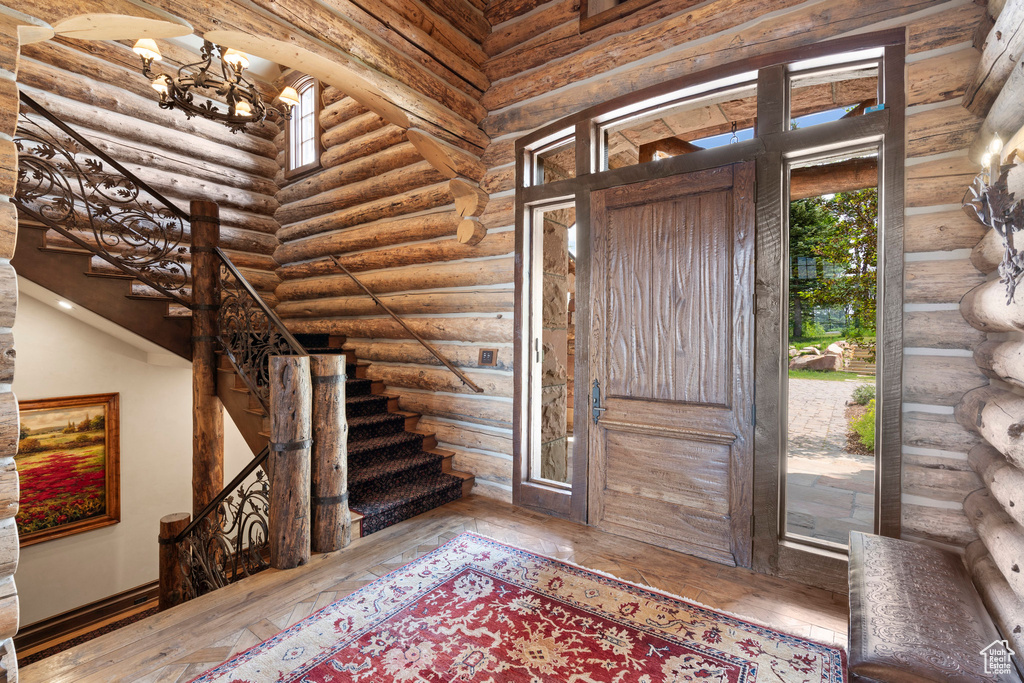Foyer with rustic walls, a chandelier, hardwood / wood-style floors, and stairway