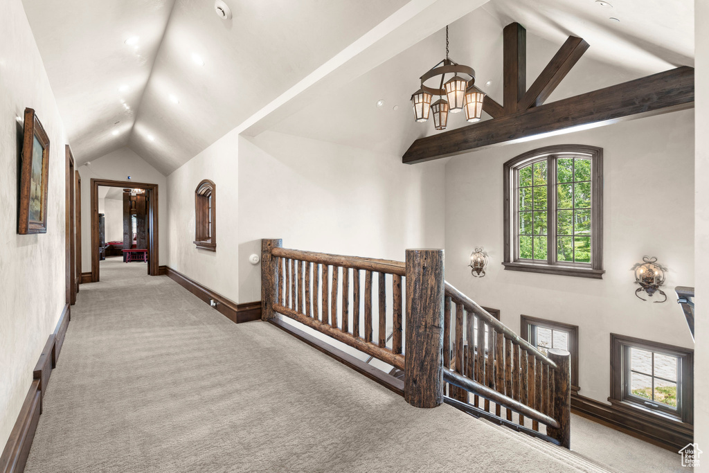 Hallway featuring lofted ceiling, carpet floors, an upstairs landing, and a chandelier