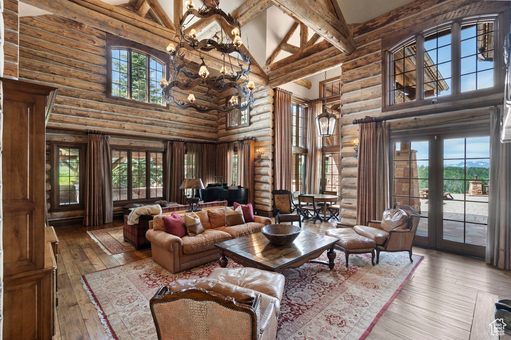 Living area featuring high vaulted ceiling, rustic walls, french doors, wood-type flooring, and beamed ceiling