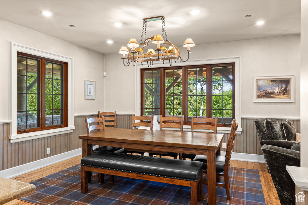 Dining area with plenty of natural light, wood finished floors, a wainscoted wall, a chandelier, and recessed lighting