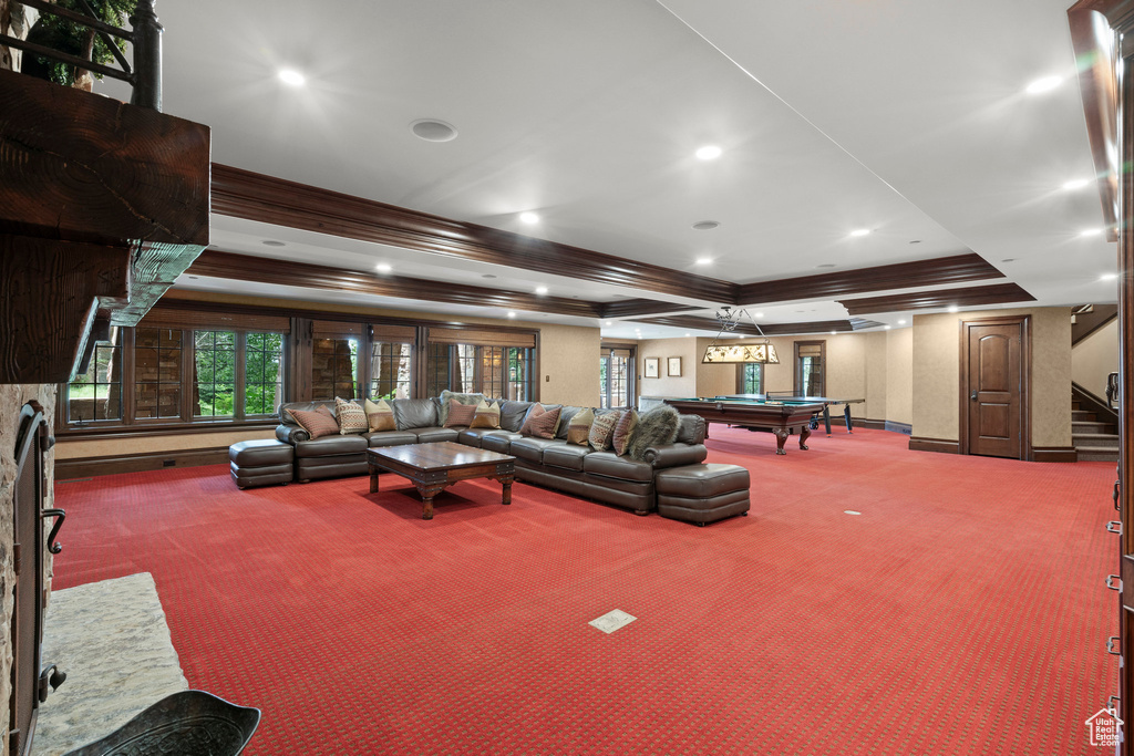 Living room with carpet floors, a raised ceiling, billiards, ornamental molding, and stairway