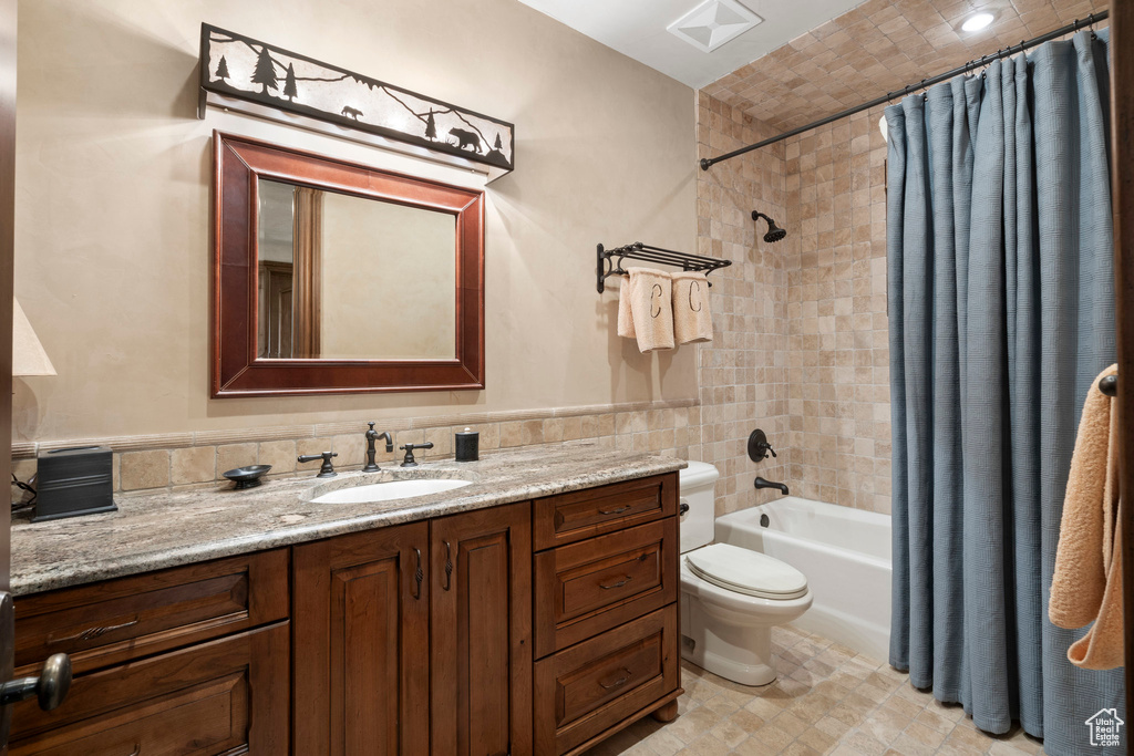 Full bathroom featuring tile walls, vanity, and shower / bathtub combination with curtain