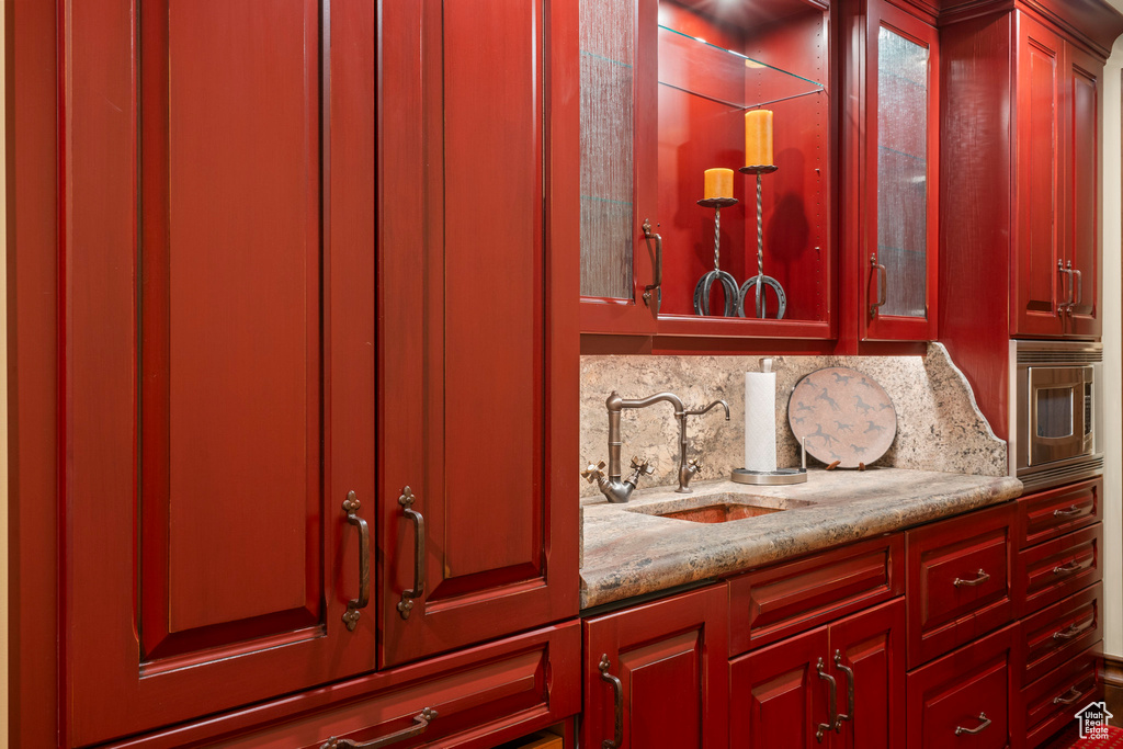 Detailed view of stainless steel microwave, bar with sink, and decorative backsplash