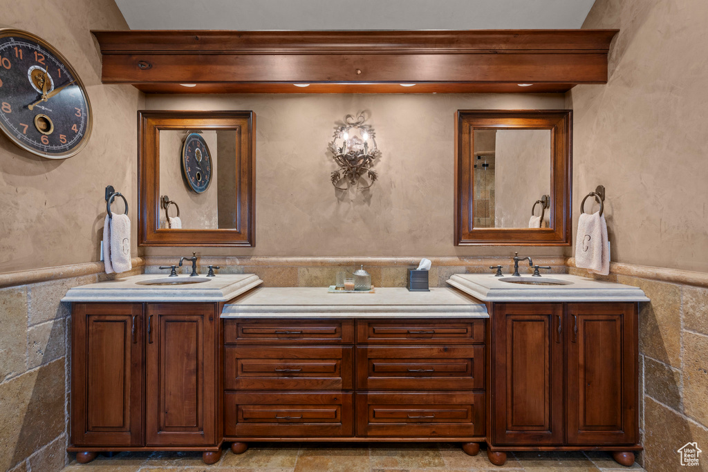 Bathroom with double vanity, wainscoting, and tile walls