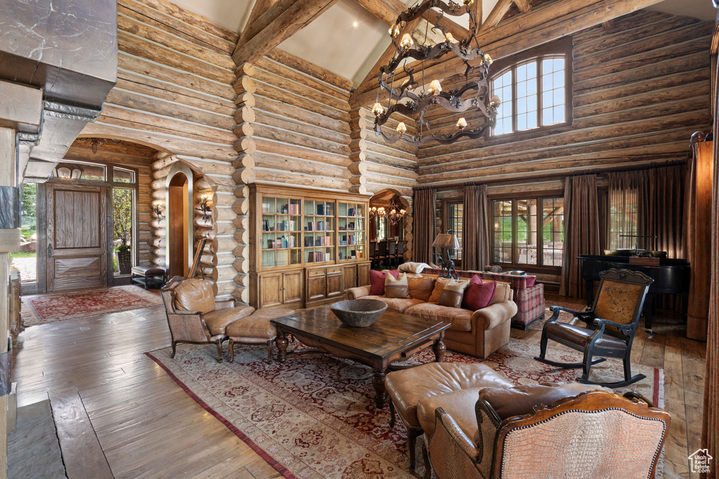 Living room with high vaulted ceiling, beamed ceiling, arched walkways, hardwood / wood-style flooring, and log walls