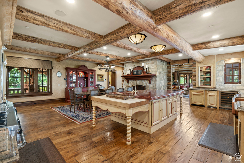 Kitchen featuring wine cooler, healthy amount of natural light, hardwood / wood-style flooring, open floor plan, and beam ceiling