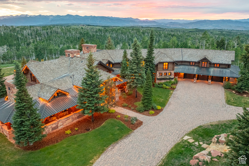 View of front of house featuring decorative driveway, a view of trees, a mountain view, and a chimney
