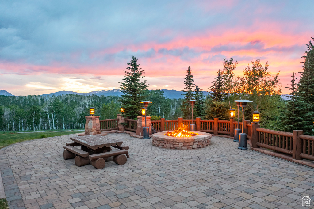 Patio terrace at dusk featuring a fire pit, a mountain view, and a patio area