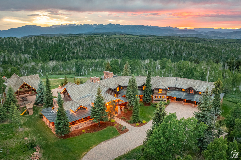 Aerial view of property and surrounding area with a heavily wooded area and a mountainous background