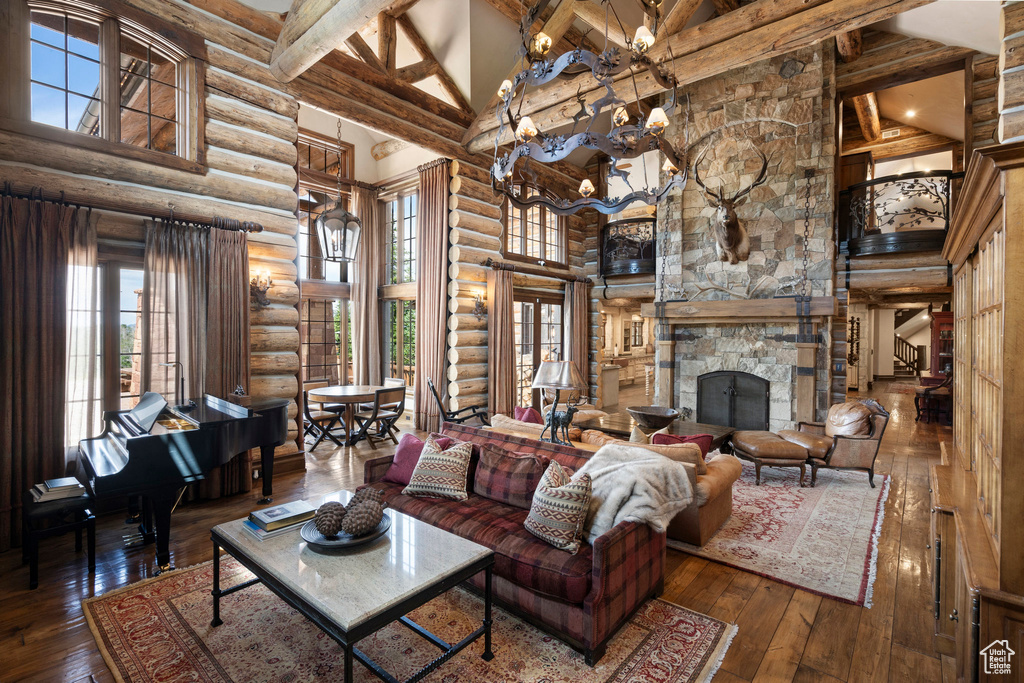 Living room with high vaulted ceiling, rustic walls, hardwood / wood-style floors, beam ceiling, and a fireplace