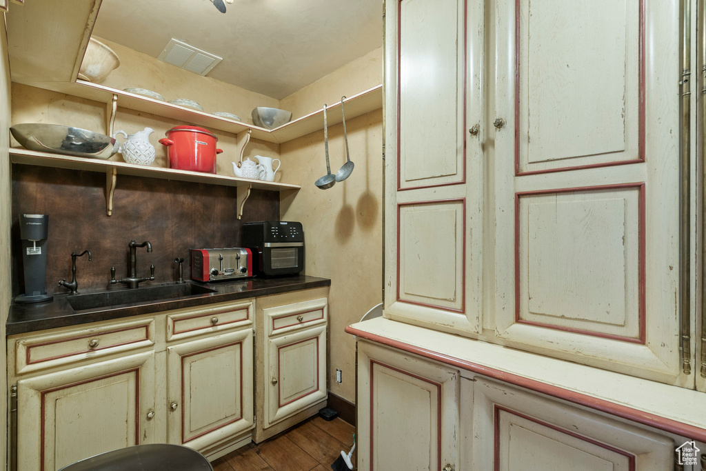 Kitchen with cream cabinets, wood finished floors, open shelves, and dark countertops
