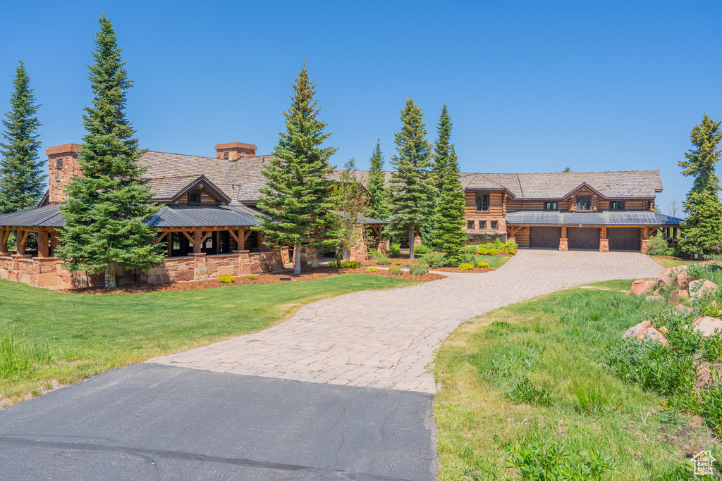 Log-style house with a standing seam roof, curved driveway, a front lawn, a metal roof, and a gazebo