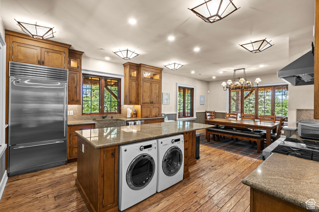 Kitchen with stainless steel appliances, separate washer and dryer, brown cabinetry, recessed lighting, and dark wood-style floors